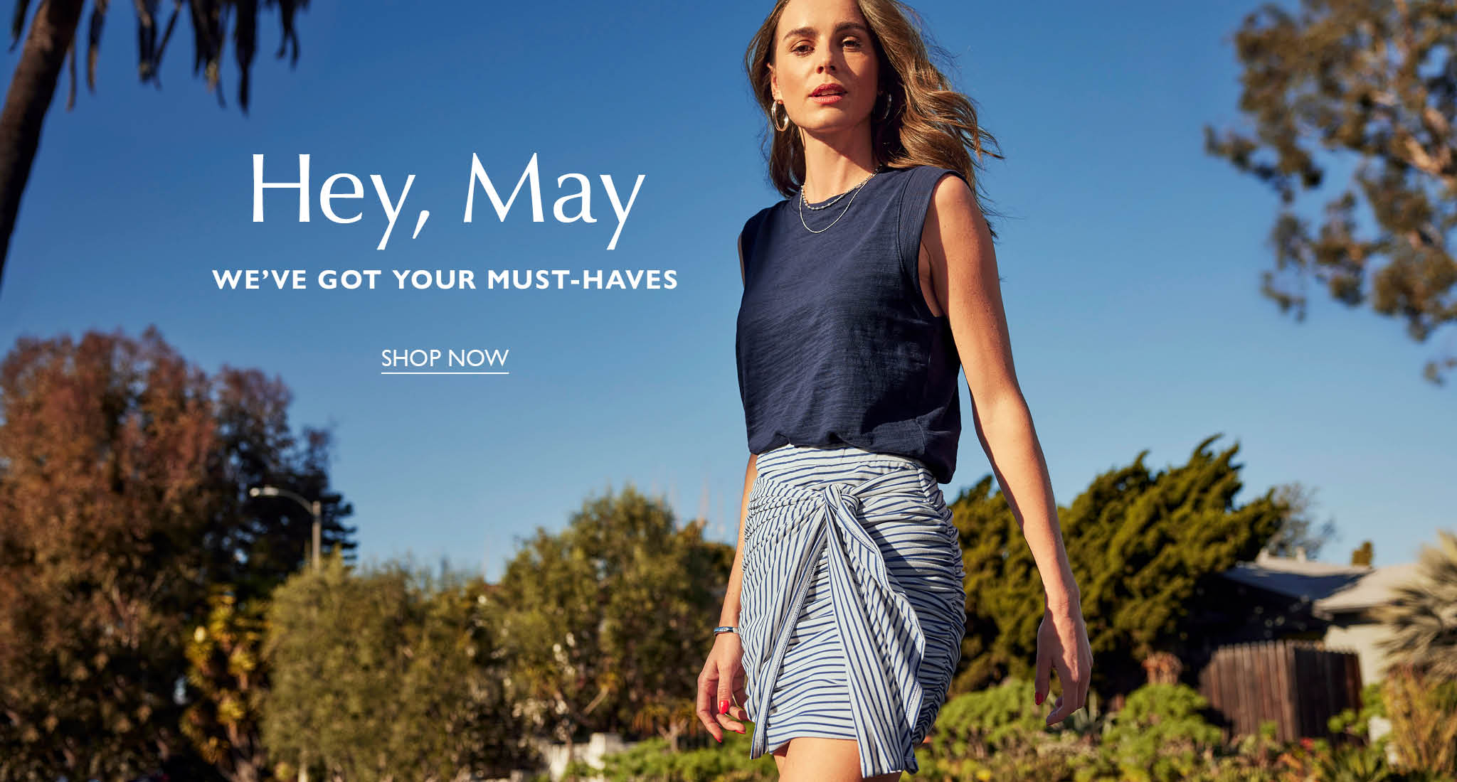 Woman with long brown hair wears a navy tank top and striped skirt with a tie in the front. - Shop Now